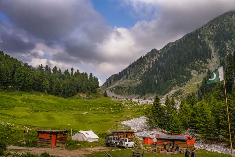 A Pakistani national flag fluttering in a scenic mountain valley