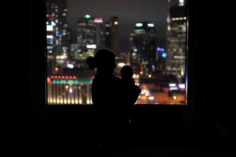 a silhouette of two people standing together looking out a window