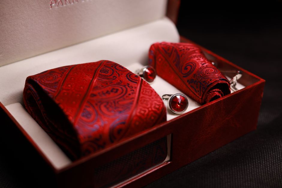 Luxury red silk necktie, handkerchief, and cufflink set displayed in a gift box for formal occasions.