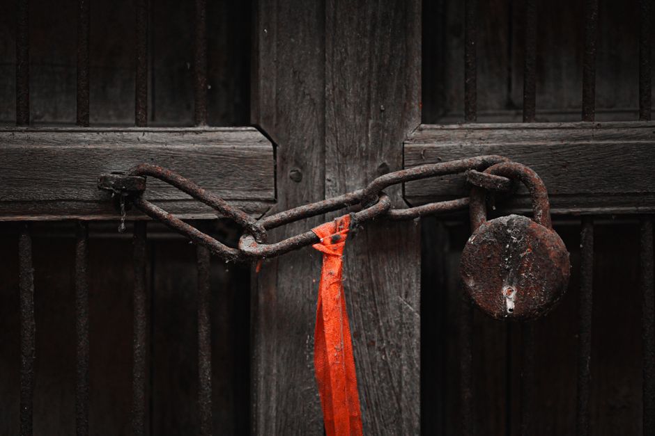 A rusty padlock and chain securing an old wooden door, symbolizing security and secrecy.