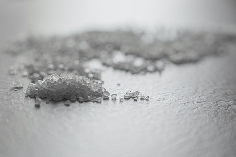 Detailed shot of coarse rock salt scattered on a textured surface.