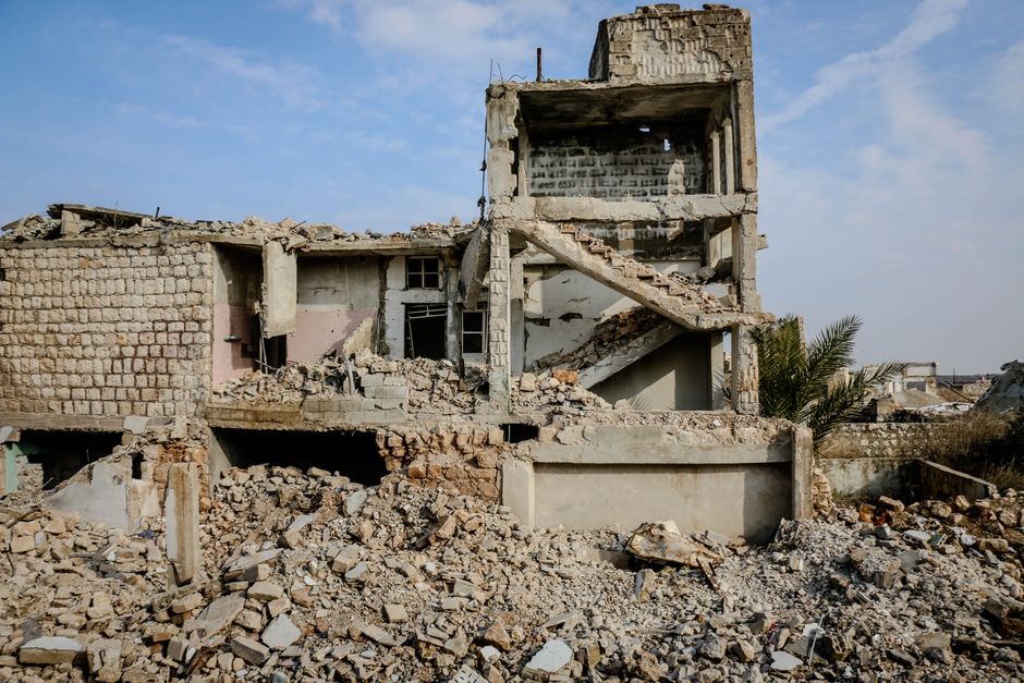 Old stone damaged house with broken walls located on street with heap of stones in poor neglected district of town