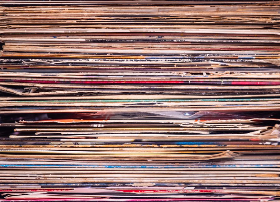Close-up view of a stack of vintage vinyl records with colorful album covers.