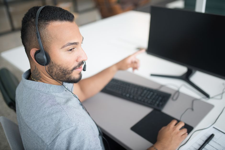Customer service agent using a computer and headset within a modern office setting.