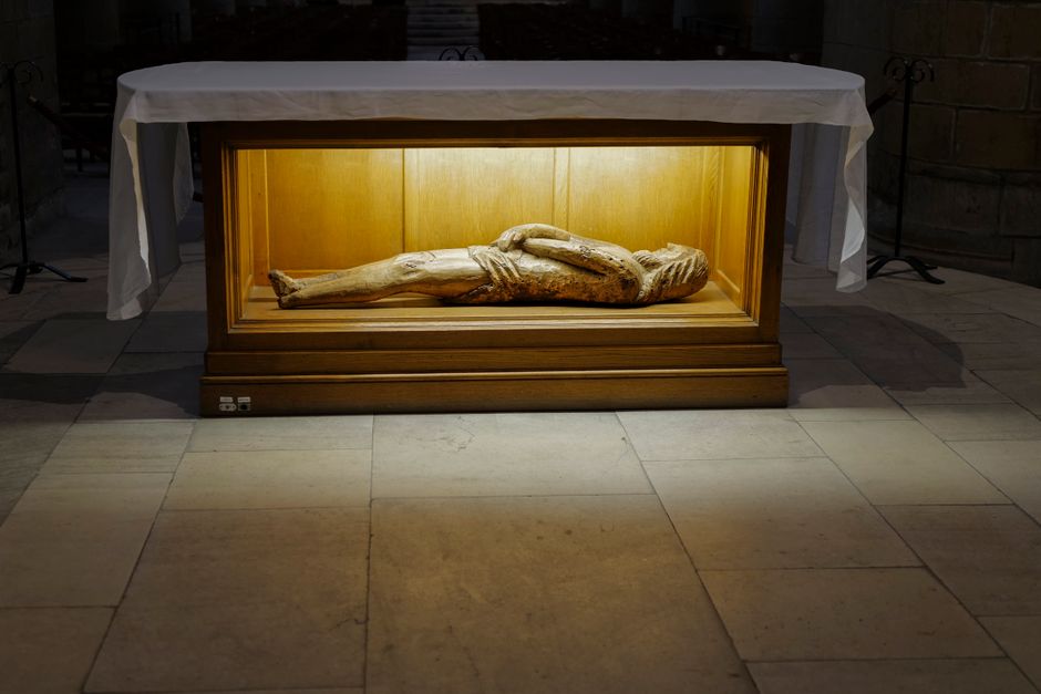 Wooden display with religious relic sculpture inside a dimly lit interior.