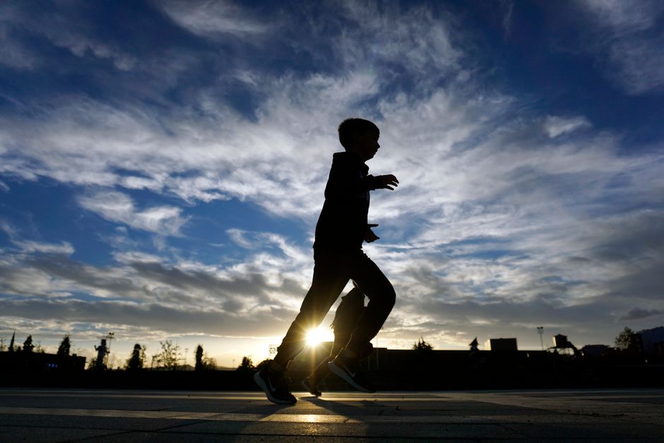 Silhouette of a boy running outdoors at sunrise, capturing youthful energy and motion.