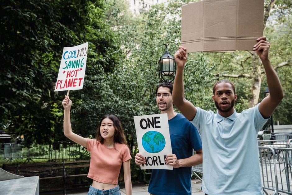 Diverse group of young activists holding signs at a climate protest outdoors.