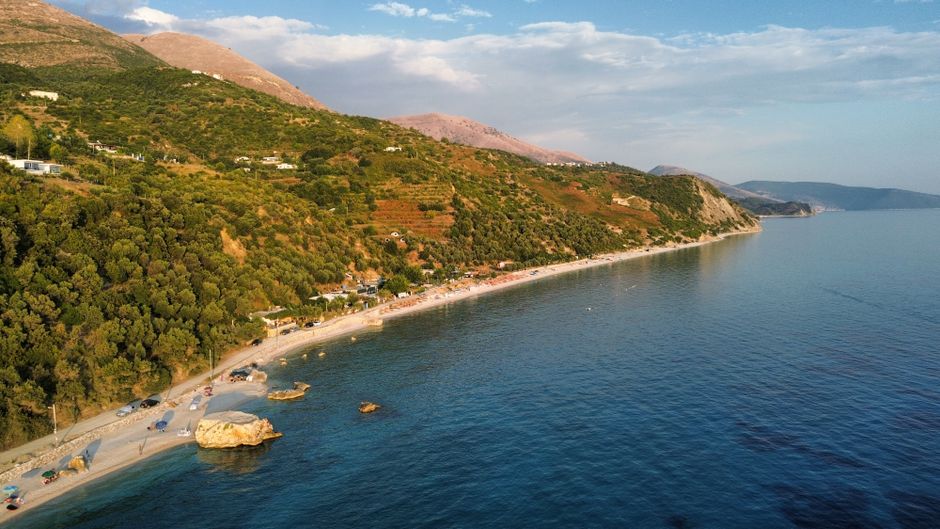 Stunning aerial view of the Albanian coastline with lush hills and clear blue sea.