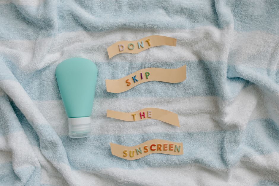 Flat lay of sunscreen bottle with message 'Don't skip the sunscreen' on a towel.