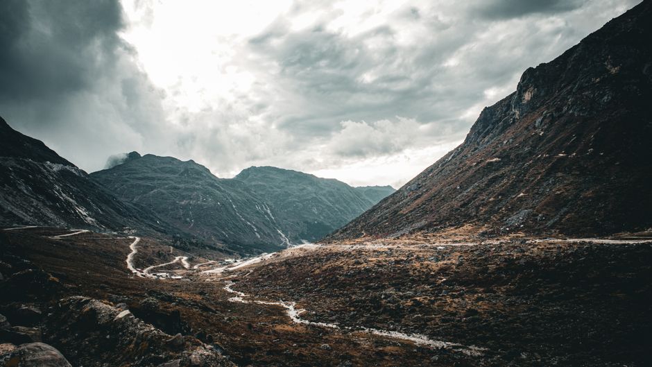 A stunning mountain pass under a dramatic cloudy sky, perfect for travel and adventure themes.