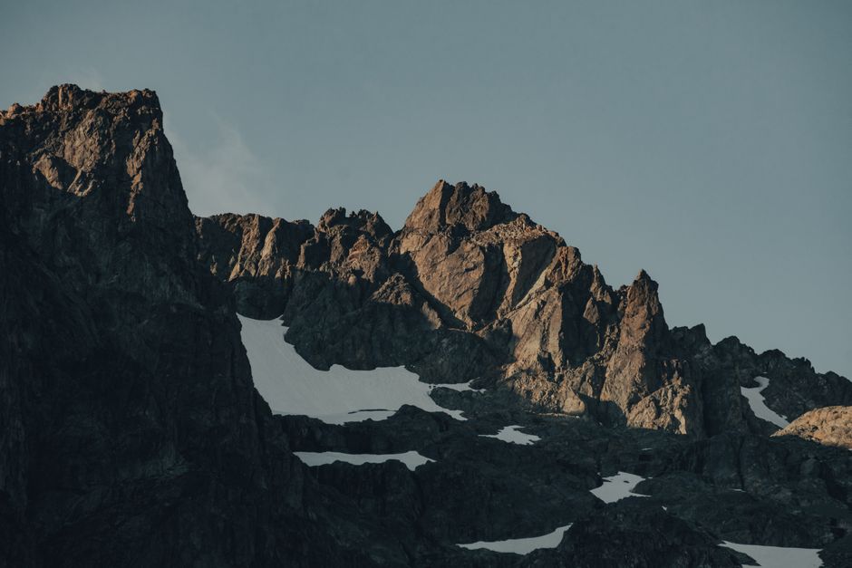 Picturesque scenery of top of rough rocky mountains covered with snow under cloudless blue sky in daytime