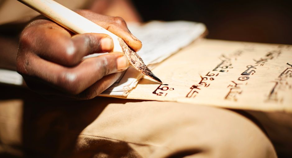 Detailed close-up of a person writing on papyrus with a traditional ink pen, highlighting cultural script.