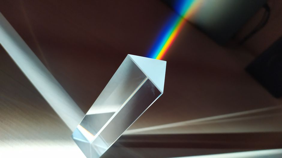A glass prism creates a vivid rainbow reflection, capturing abstract geometric beauty.