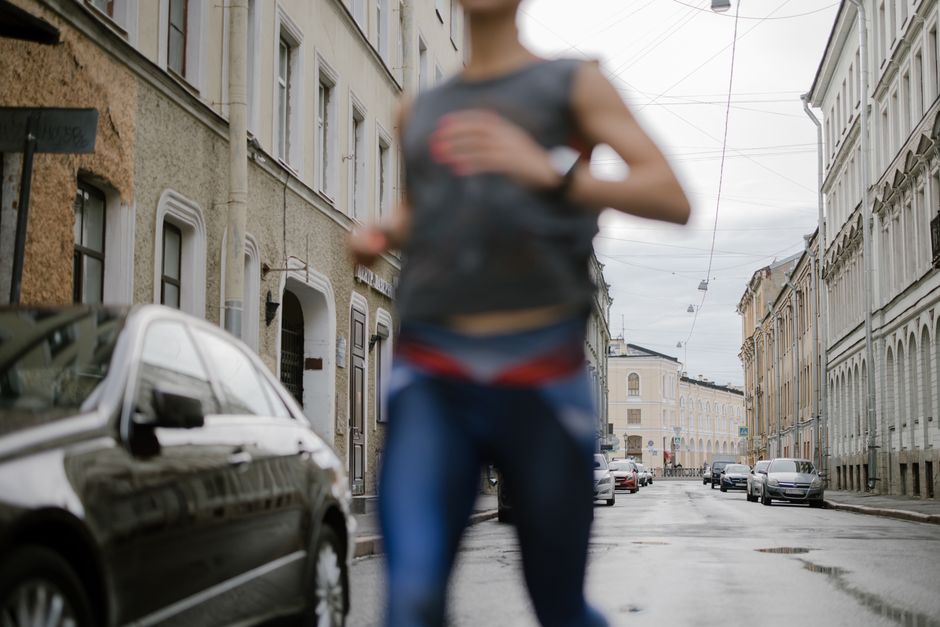 A blurred runner in activewear dashes through a serene urban street, symbolizing vitality.