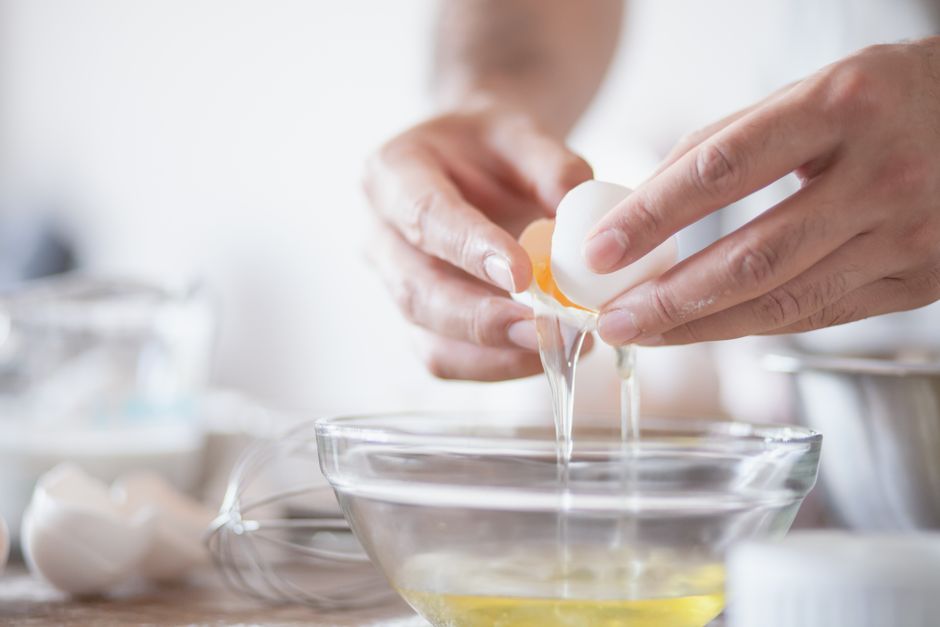 Hands carefully separating egg yolks and whites into a bowl, perfect for culinary content.