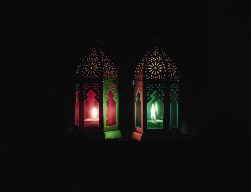 Traditional Islamic lanterns with lit candles creating a warm ambiance in darkness.
