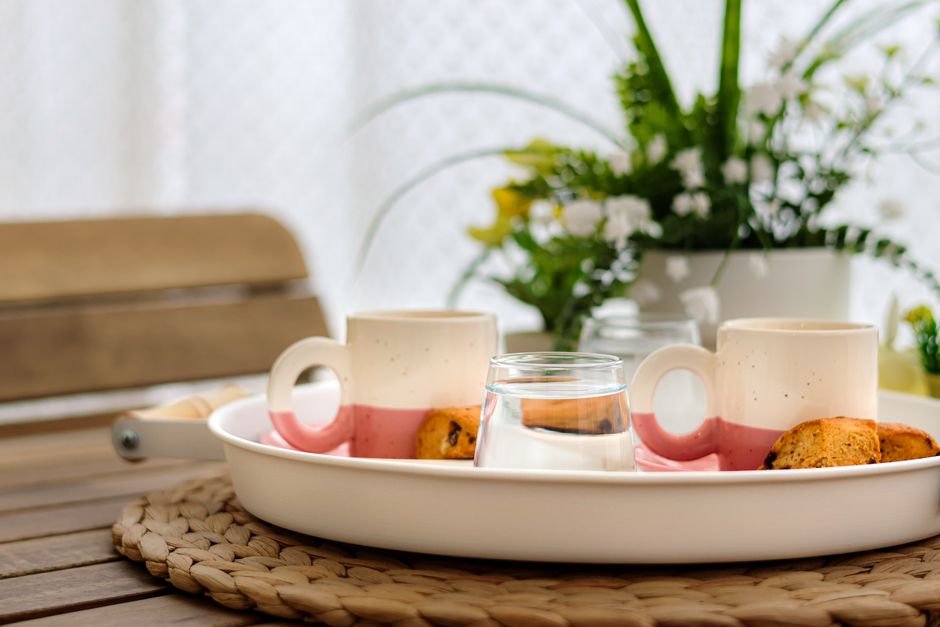 A warm and inviting coffee setup with two cups, cookies, and floral decor on a wood table.