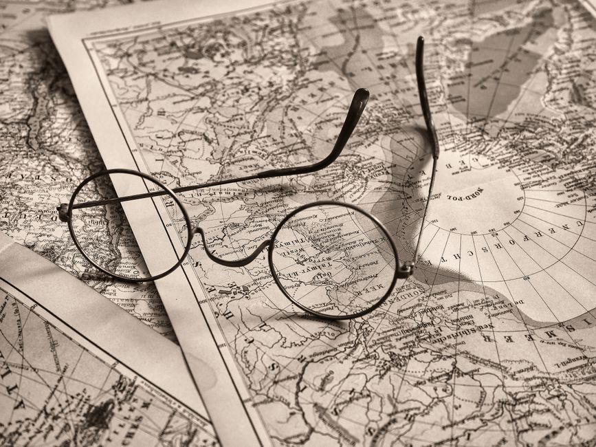 Round eyeglasses rest on an antique world map, evoking a sense of exploration.
