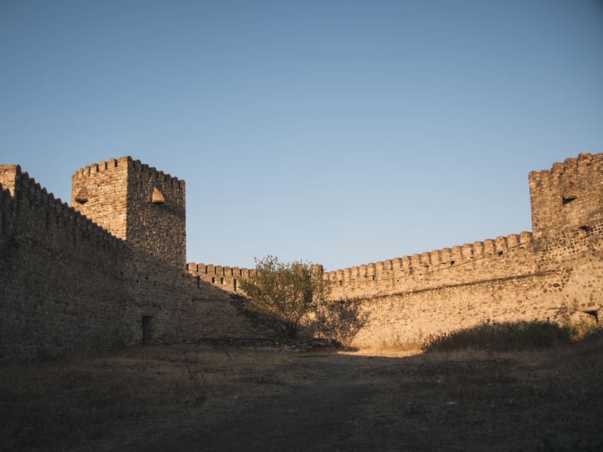 A historic fortress with robust stone walls under a serene blue sky, showcasing medieval architecture.