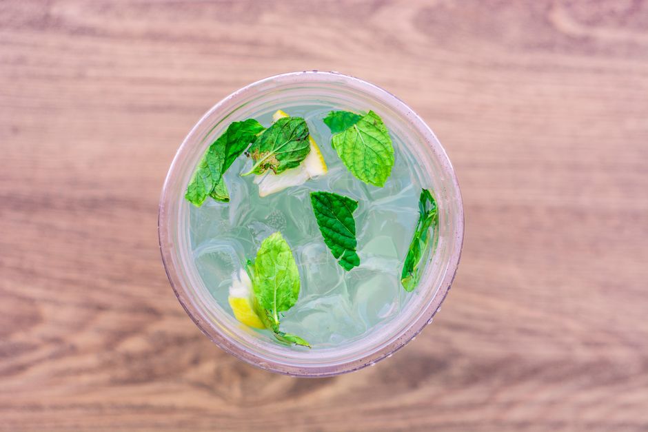 A refreshing iced drink with lemon and mint leaves viewed from above.