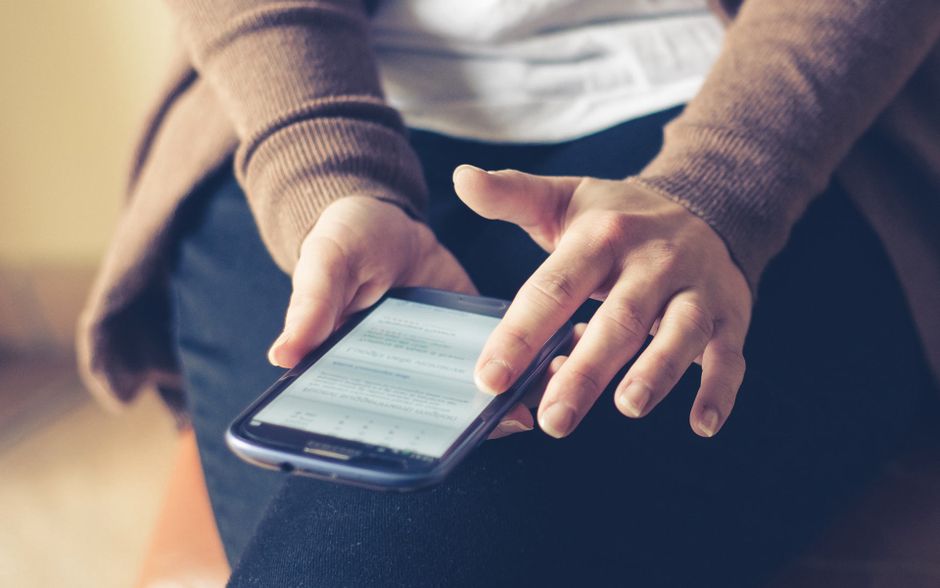 Close-up of adult using smartphone indoors, browsing web with focus on screen.