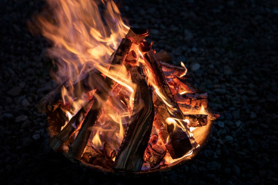 A close-up view of logs burning in a vibrant campfire, illuminating the night outdoors.