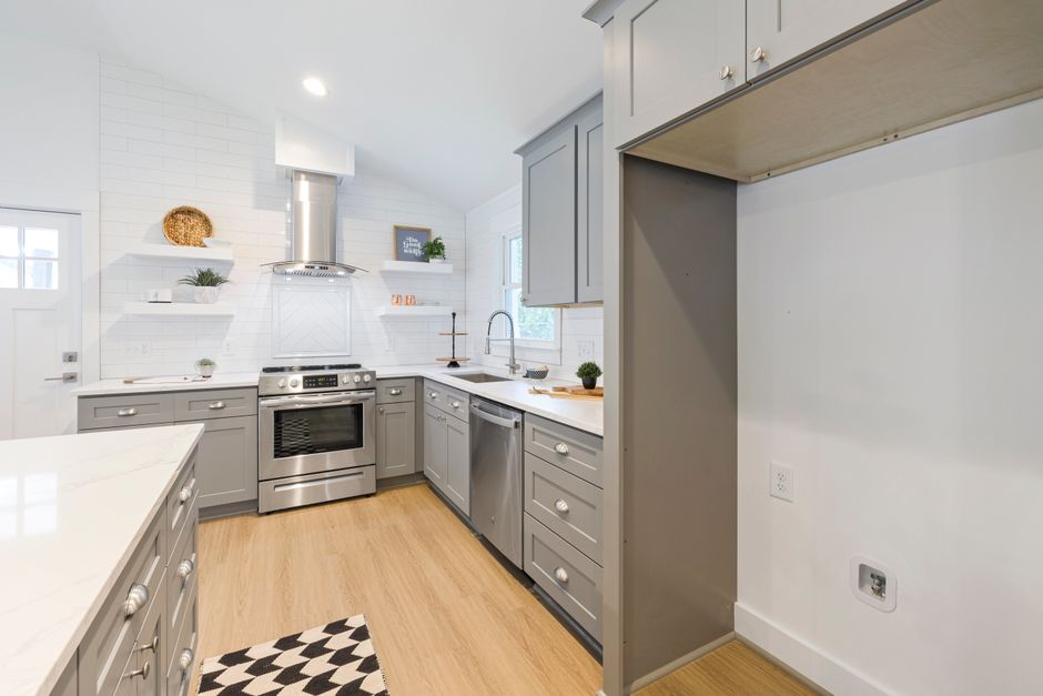 A sleek, minimalist kitchen with grey cabinets and stainless steel appliances.
