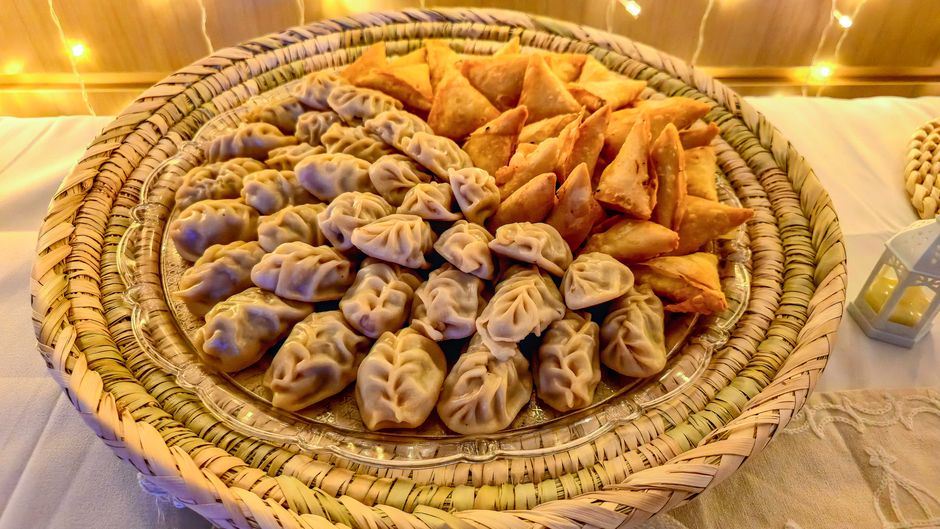 A delicious assortment of dumplings and samosas elegantly displayed on a wicker tray.