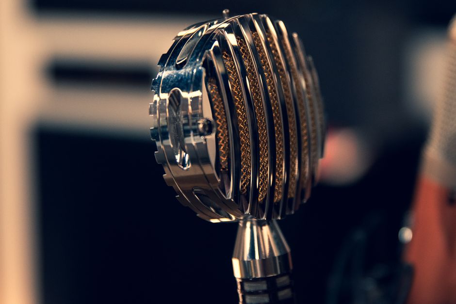 Close-up of a vintage condenser microphone in a recording studio with a focus on intricate details.