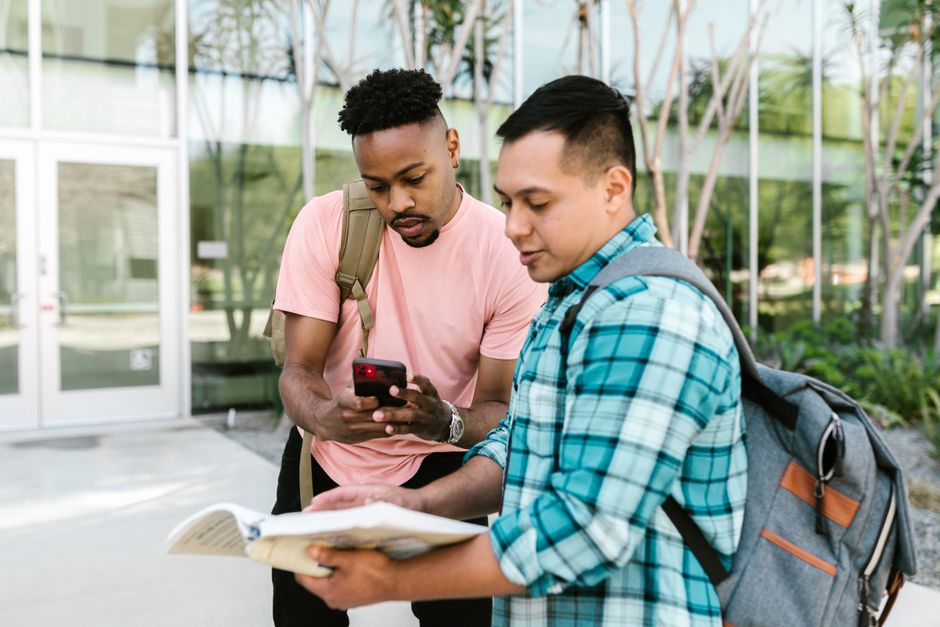 Two students reviewing notes on campus, collaborating for an exam outside.