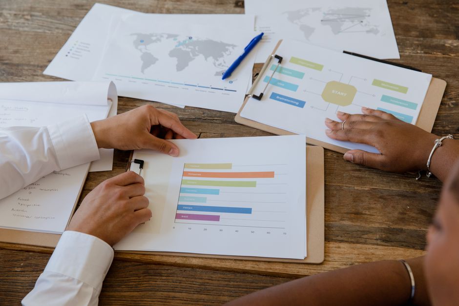 Top view of colleagues discussing charts and graphs on a wooden table during a business meeting.