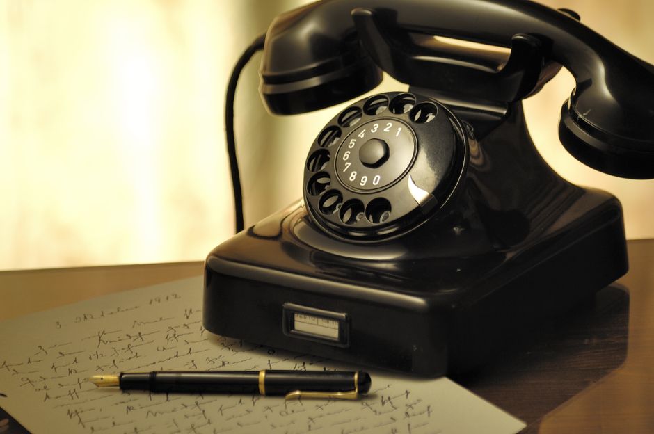 A nostalgic scene with an antique rotary phone and a fountain pen on a desk.