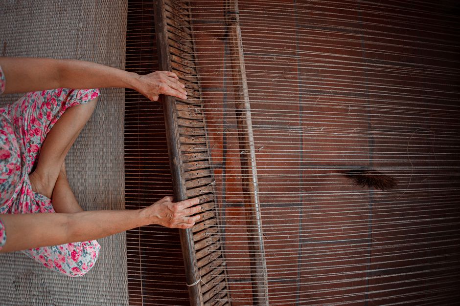 A person weaving fabric on a traditional wooden loom, showcasing intricate craftsmanship.