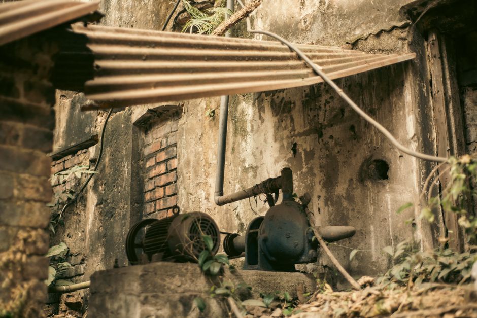 Aged industrial machinery in an abandoned outdoor setting with weathered textures.