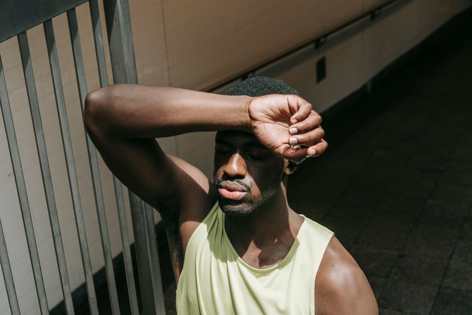 Portrait of a man in a yellow tank top with eyes closed, enjoying sunlight.