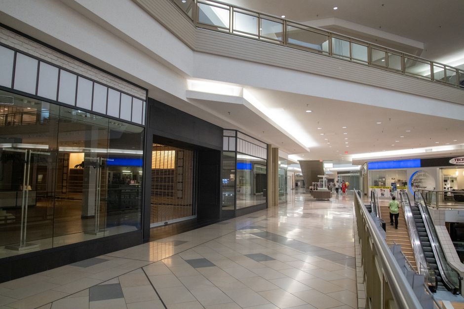Spacious and contemporary mall interior with closed stores and escalator.