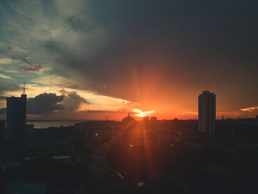 Experience the breathtaking city skyline silhouetted against a vibrant sunset sky with dramatic clouds.