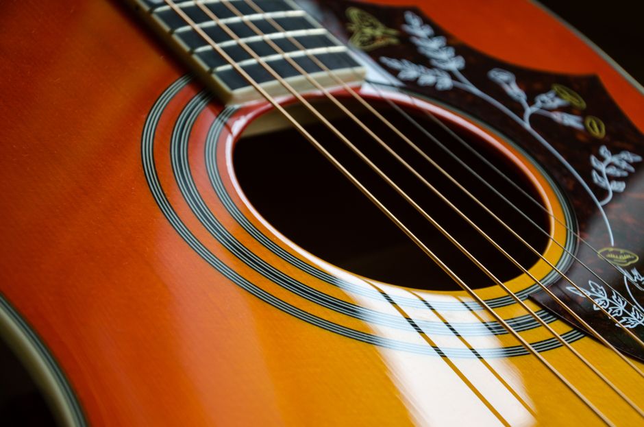 Detailed view of an acoustic guitar's strings and sound hole with intricate design.