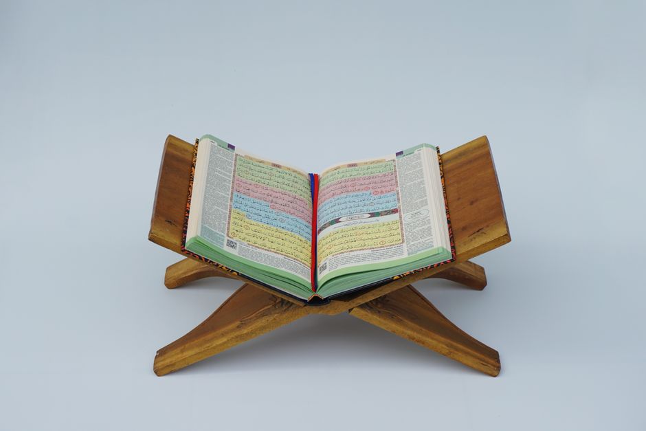 An open Quran displayed on a wooden stand, symbolizing Islamic faith and spirituality.