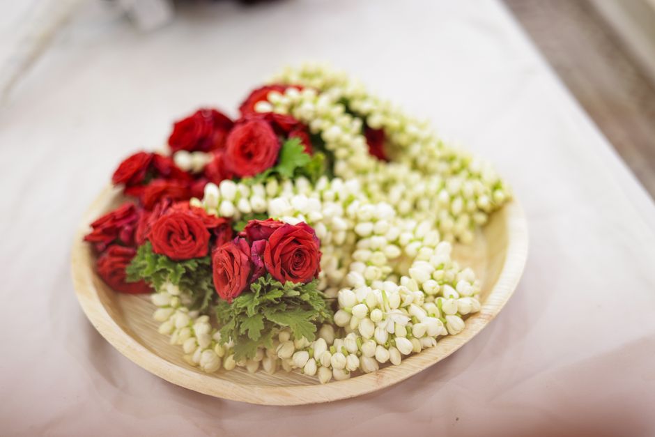 A vibrant arrangement of red roses and jasmine on a tray, perfect for weddings.
