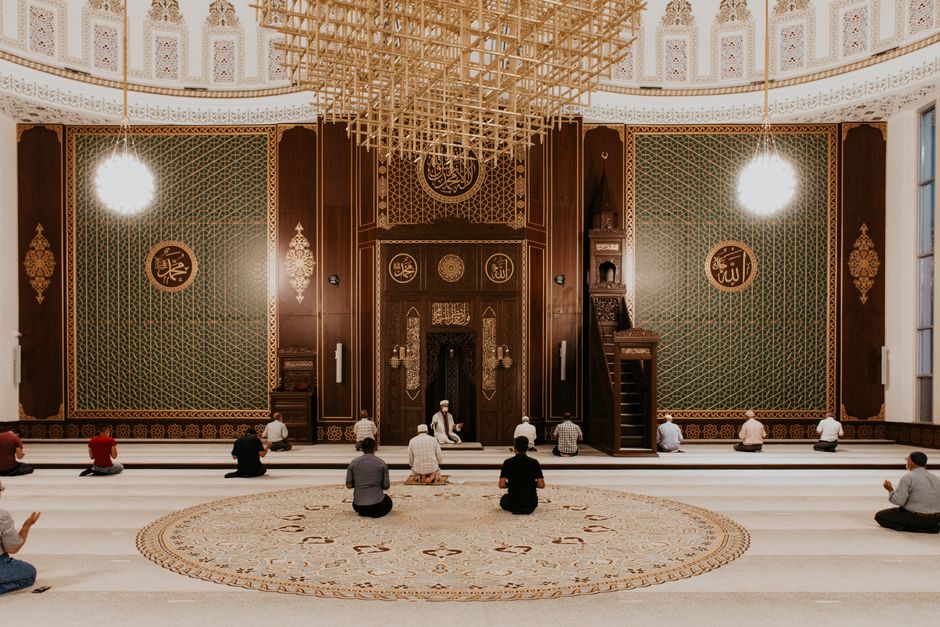 A beautifully ornate mosque interior with individuals engaged in prayer, capturing serenity and devotion.