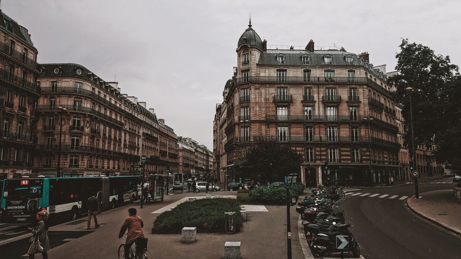 Charming Paris street scene with historic architecture, vehicles, and pedestrians. Captures urban life in Paris.