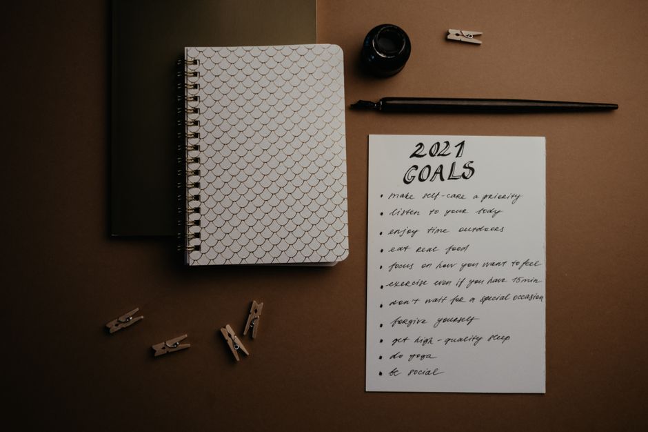 Aesthetic flatlay of notebooks and a 2021 goals list in elegant calligraphy.