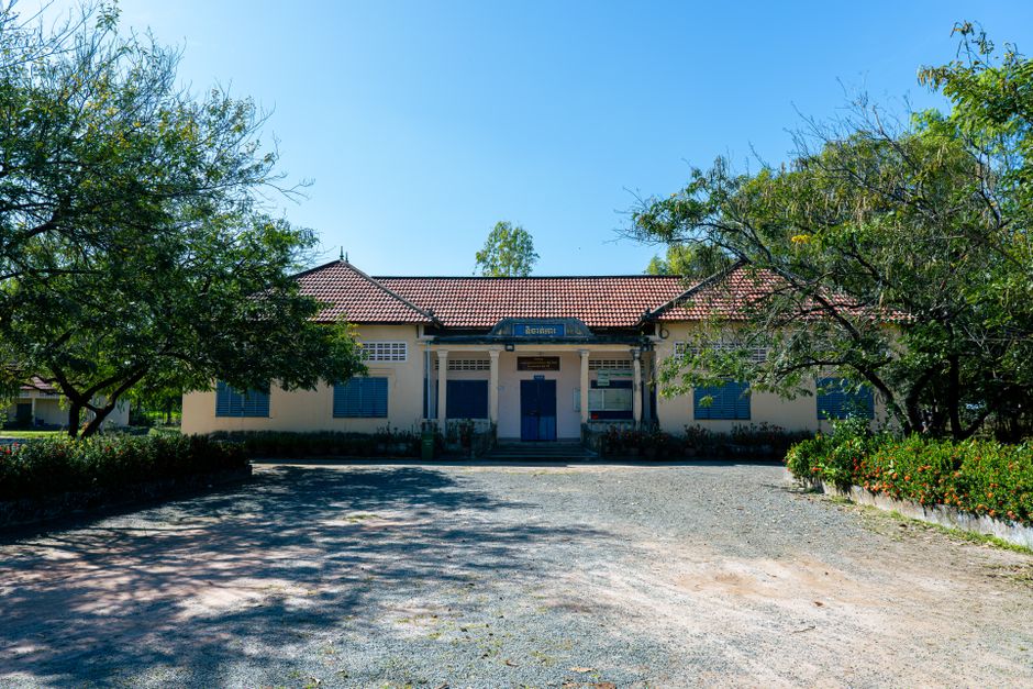 A charming colonial-era building surrounded by lush trees under a clear blue sky, exuding a peaceful ambiance.