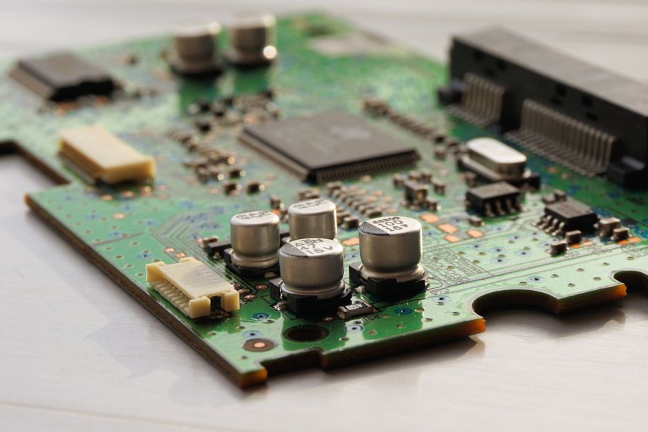 Detailed view of a green circuit board featuring capacitors and microchips.