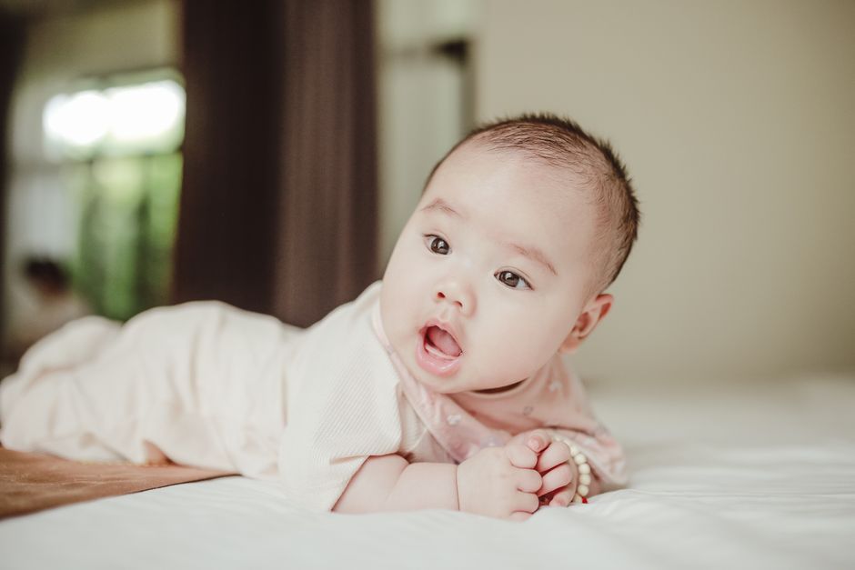 Cute baby lying on bed, looking curiously. Perfect for family and lifestyle themes.