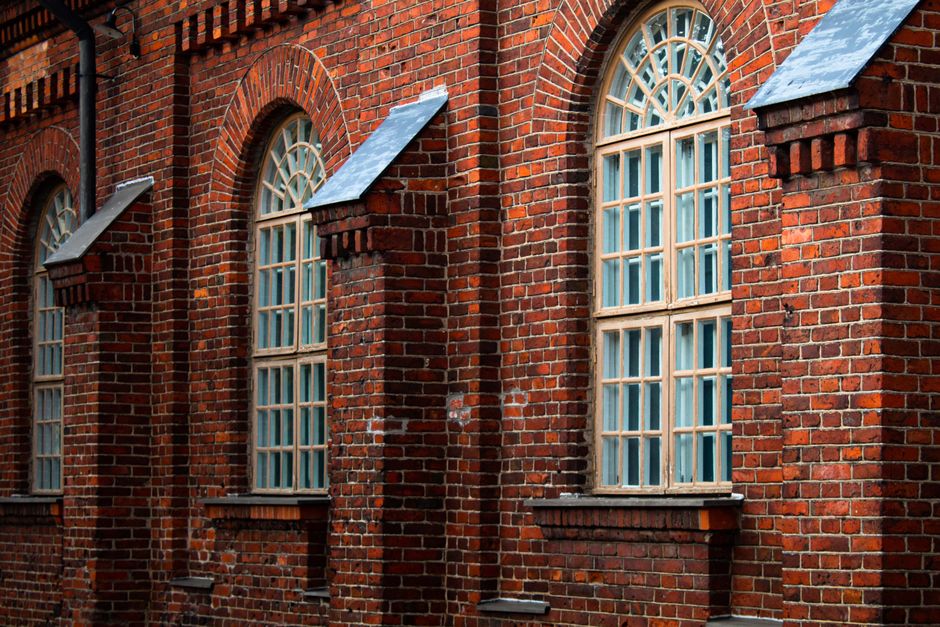 Detailed view of a historic brick building facade with arched windows, showcasing architectural design.