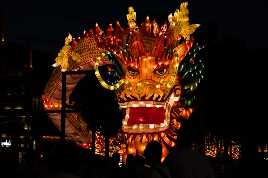 Colorful dragon lantern illuminates the night sky during a festival celebration.