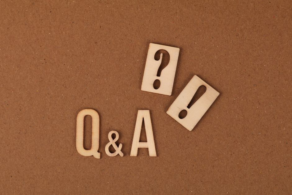 Wooden cutouts of Q&A with question and exclamation marks on a brown backdrop.