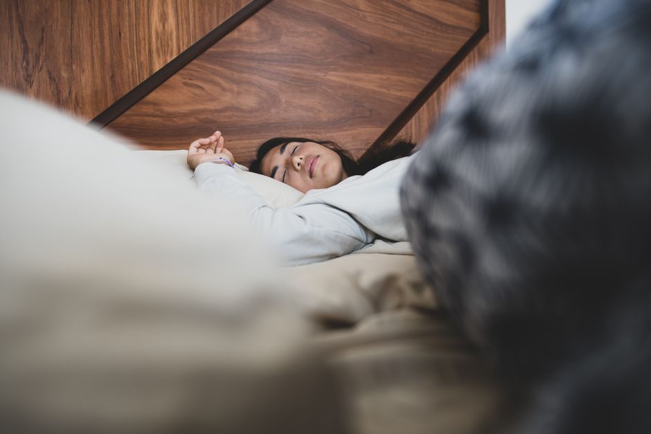 A woman peacefully sleeping on a bed, conveying relaxation and comfort.